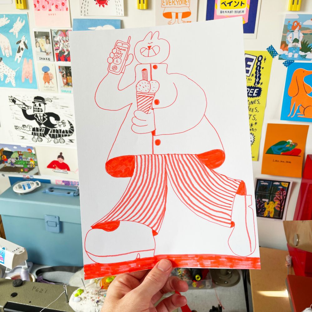 Photo of a felt tip pen drawing in red ink on white A4 paper. The drawing is of a cat person walking with a mobile phone in one hand and and ice cream in the other. They are grinning and are wearing a coat, trousers and boots. 