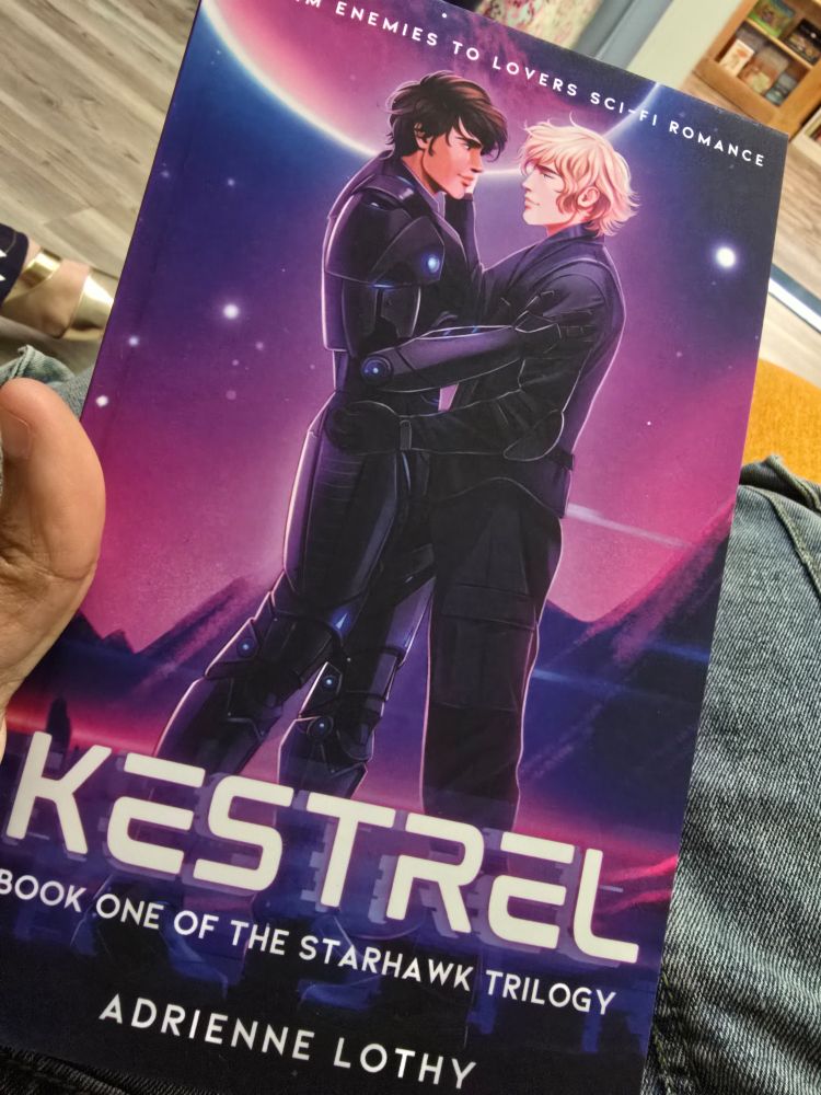 A book with 2 men in space suits in an embrace  the book is Kestrel book one of the star hawk trilogy by Adrienne lothy