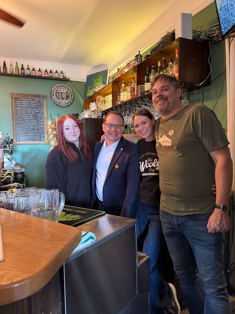 Mike posing for a photo with the crew of the Wooly behind the bar.
