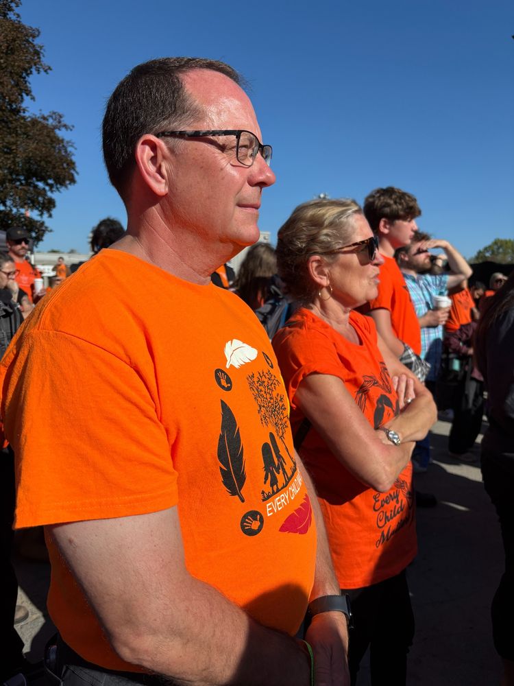 A photo of Mike and Kathleen Wynne listening to the speakers outside in the crowd.
