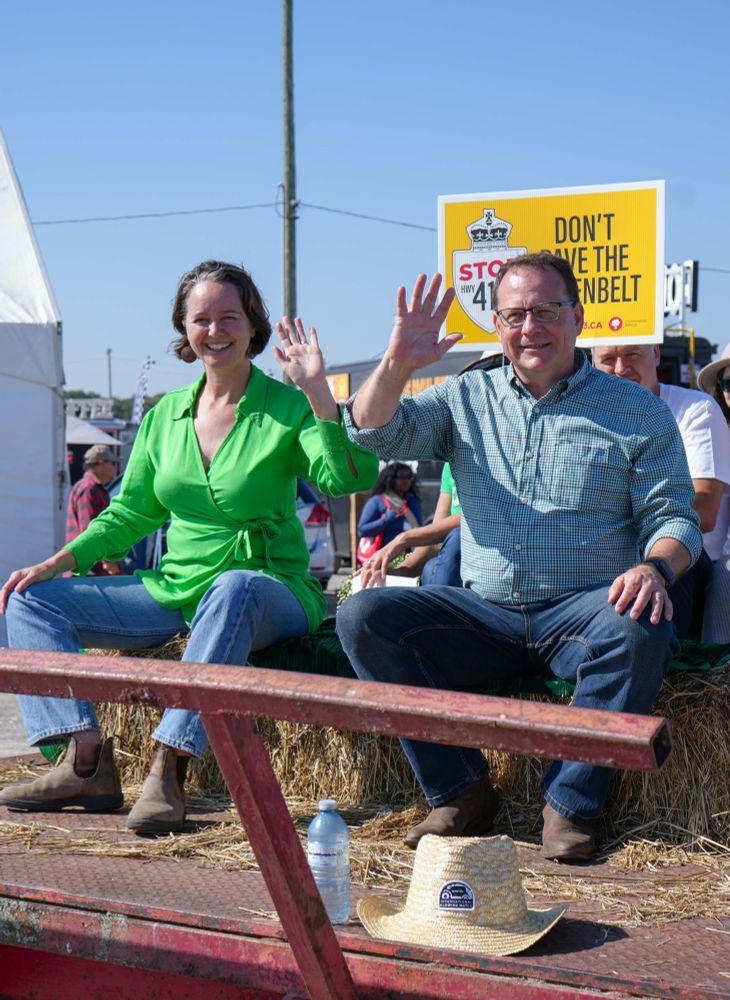Mike and Aislinn Clancy waving to camera sitting on the Green float.
