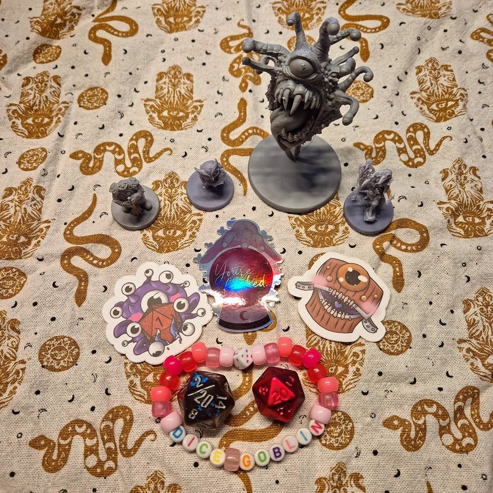 Miniatures of a beholder, some stickers of a cute beholder, mimic and a crysyal ball. And a bracelet that says Dice Goblin.