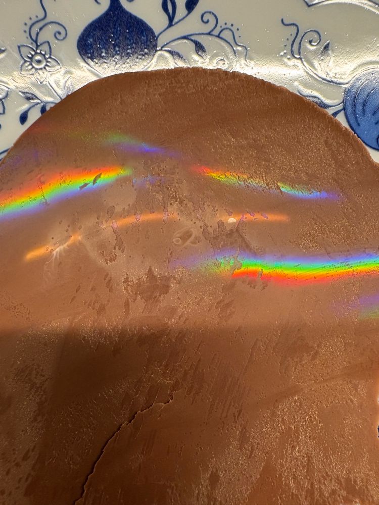 Plate with some thin milk chocolate that has a fine grating on the surface leading to rainbows shimmering under a light source 
