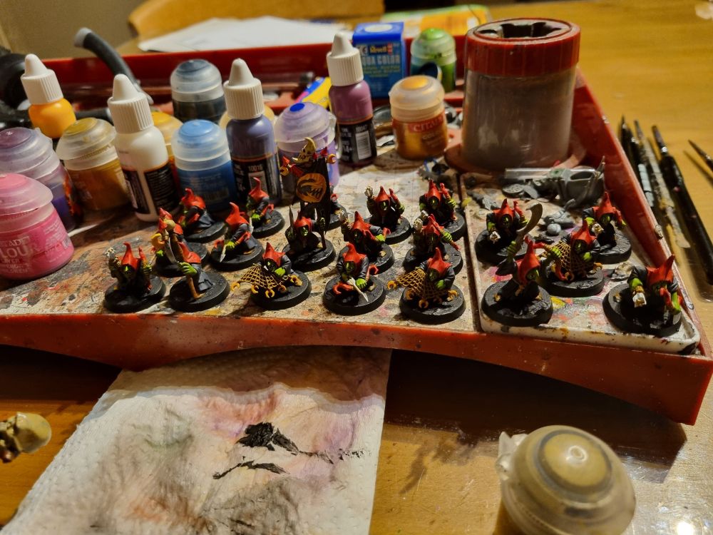 A messy painting desk with 20 completed goblins.