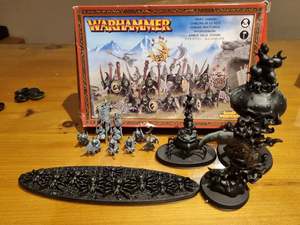 8 assembled goblins in front of a classic whfb night goblin box. Next to them, the endless spells are sprayed black with some liquid greenstuff on them.