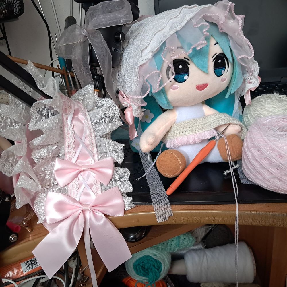 crafty photo of plushie Hatsune Miku wearing handmade lolita headpiece and wip crocheted off white and pastel pink dress and next to that big human lolita headpiece 