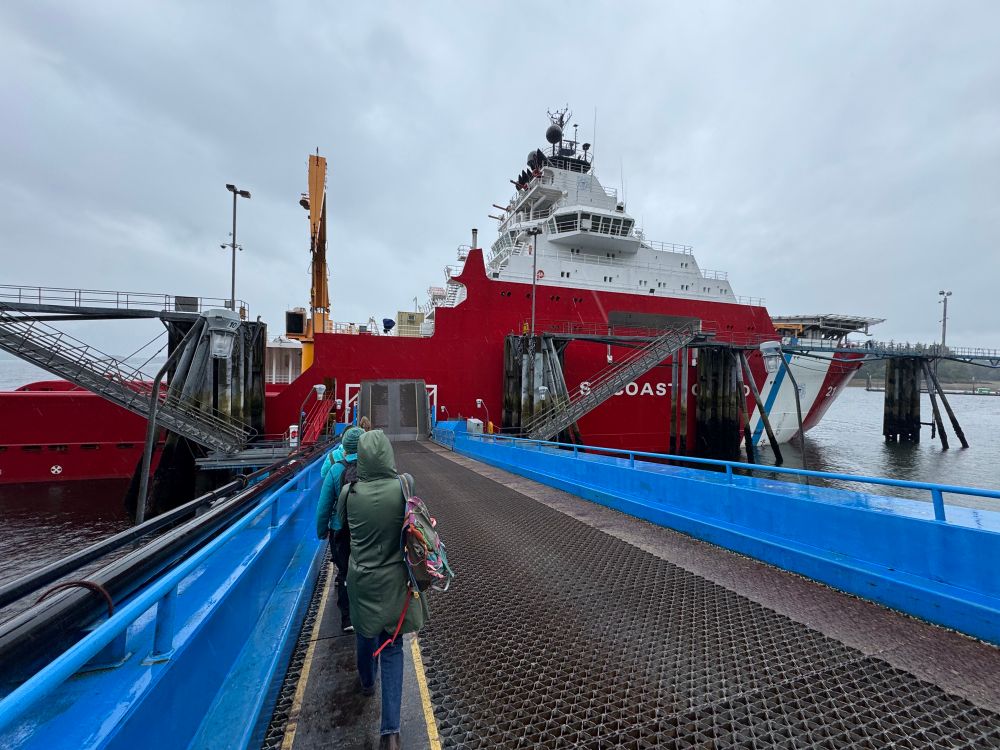 People walk toward a large red and white ship