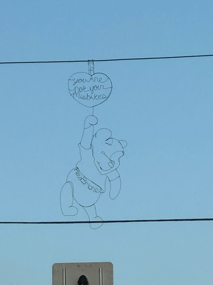 Wire hanging of Winnie the Pooh suspended from a traffic light wire