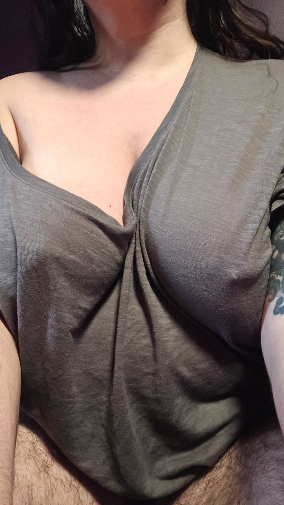 Nonbinary FTM femboy fairy Stellaris sitting in bed after waking up, their soft hairy thighs exposed. Their arms push their tits together, which are barely contained by the thin, semi-see through, worn out pajama shirt they're wearing. It's so thin and worn that their aurora crystal nipple piercings are shining right throigh it, and you can see the outline od their pierced nipples clearly. A truly wonderful way to wake up!