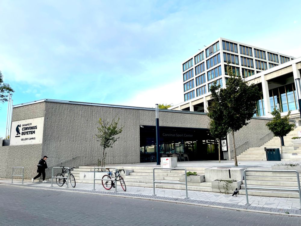 The entrance to Gellert Campus, Corvinus University. Stone steps in front of a large concrete and glass building.