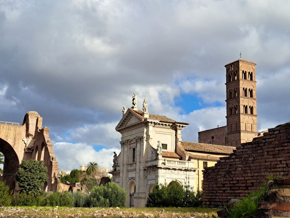 Blick im Forum Romanum auf alte Kirche und Kirchturm bei goldenem Sonnenlicht