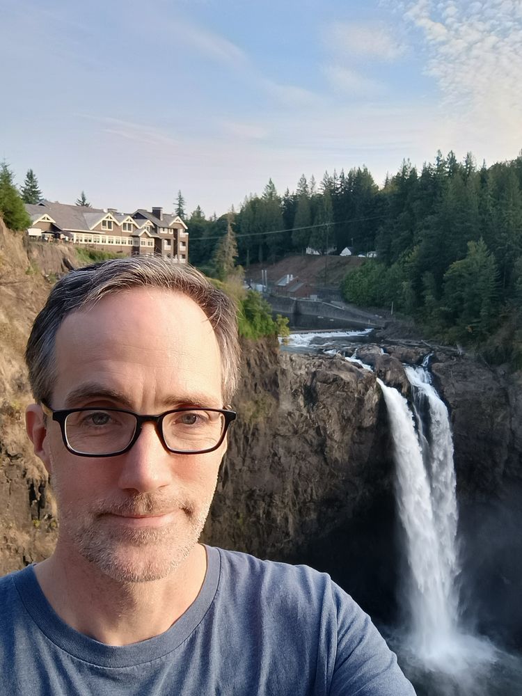 A grinning man near a waterfall 