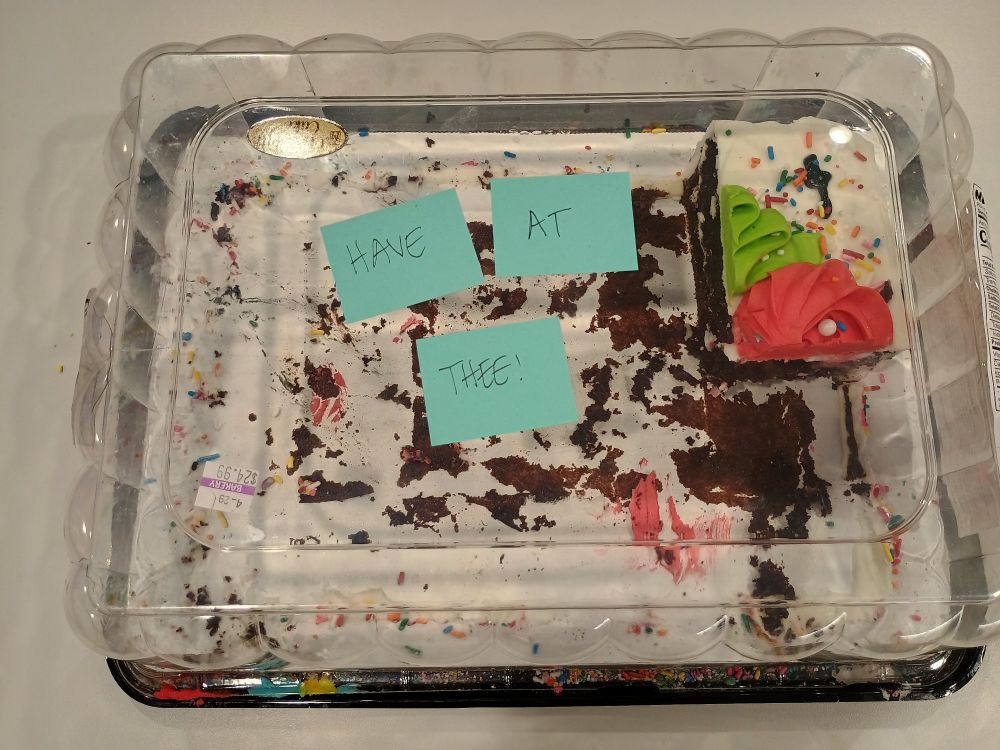A note on a cake that says HAVE AT THEE