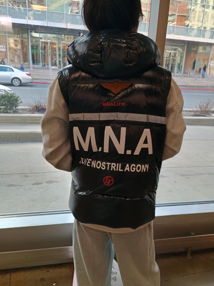 A dude wearing a big coat that says M.N.A MUTE NOSTRIL AGONY which is an obscure Doors lyric. 