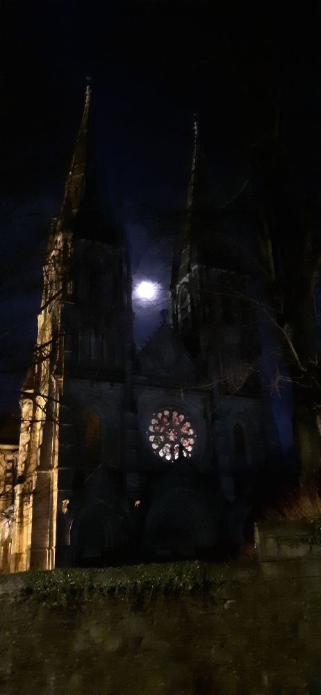 Moon between spires of cathedral with light of rose window