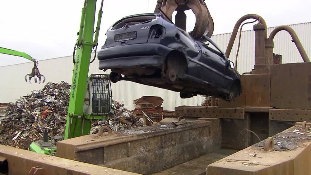 Schrottpresse in die ein Autowrack gelegt wird.