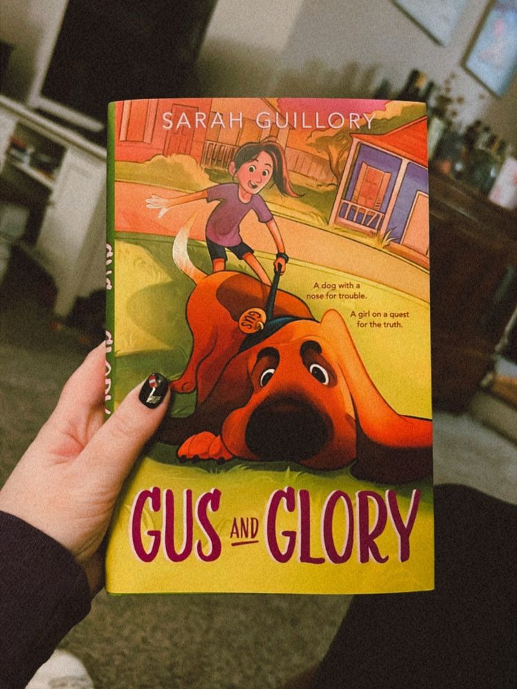 A hand holds a hardcover copy of the book Gus and Glory by Sarah Guillory