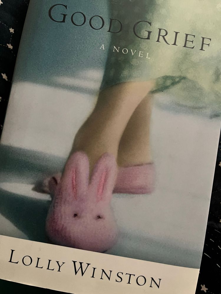 Cover of the book Good Grief by Lolly Winston. Image is a pair of legs in blue pants with the feet in pink bunny slippers. It’s a great book. Everyone should read Lolly Winston. 
