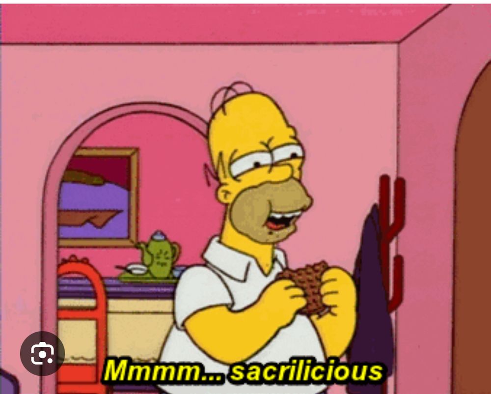 Homer Simpson, standing in front of his front door, eating something and drooling. Yellow text reads “Mmmm…sacrilicious”