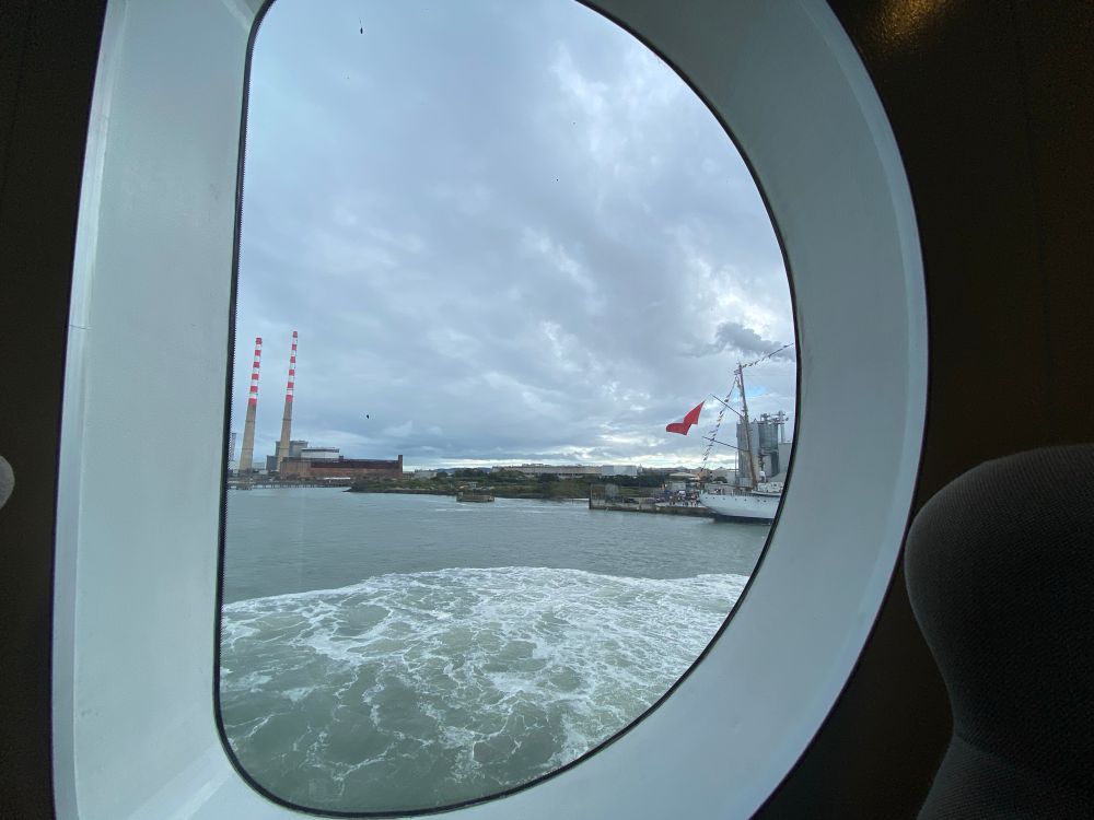 A view out the window of a ferry, with the PoolBeg Chimneys visible 