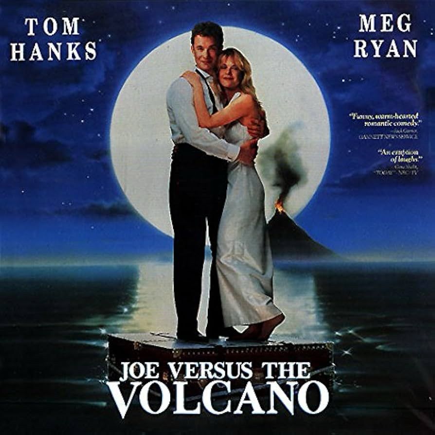 Movie poster for Joe Versus The Volcano. A man and a woman standing on a suitcase floating in the ocean. In front of a huge moon with a volcano in the distance 