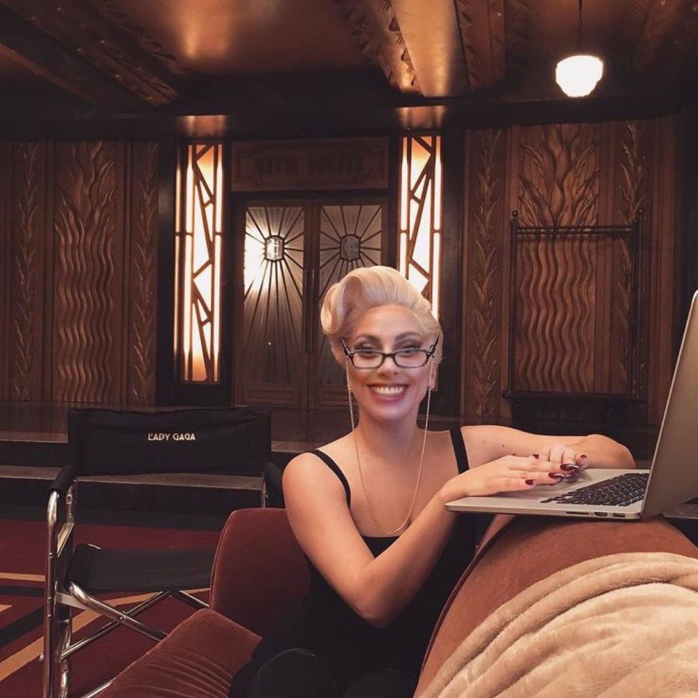 We as gay people get to choose the underrated albums we defend to the grave!!! Lady gaga in the ahs hotel on a laptop with glasses on and smiling