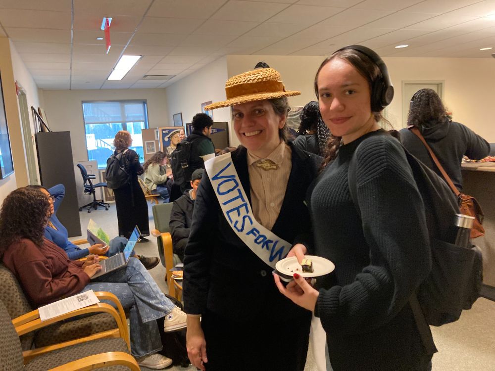 A faculty member wearing a suffragist Halloween costume and a student pose in a gathering in the history department.