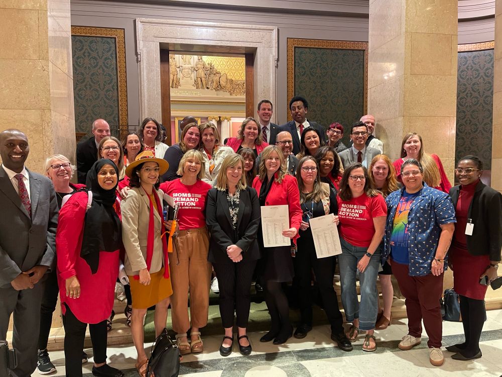 DFL Leader Melissa Hortman, in a black suit, stands with other legislators, Moms Demand Action volunteers, and GVP advocates after a late night session at the MN Capitol in 2024.