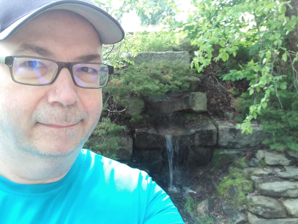 Handsome man posing for selfie in front of a waterfall