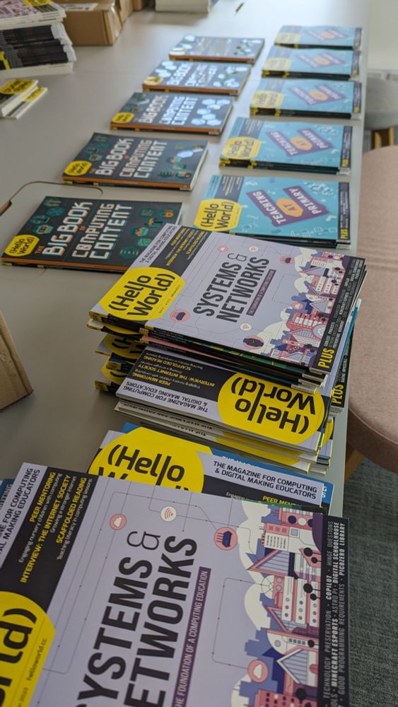 A table stacked with Hello World magazines, a free magazine for computing or computer science educators.