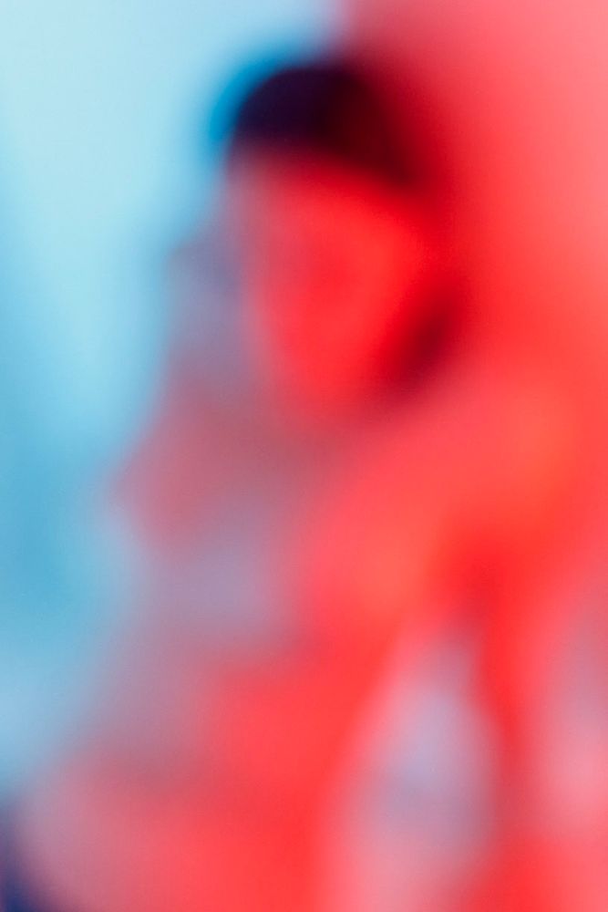 Silhouette féminine floue et dénudée sous la douche. La lumière est rouge et bleue.