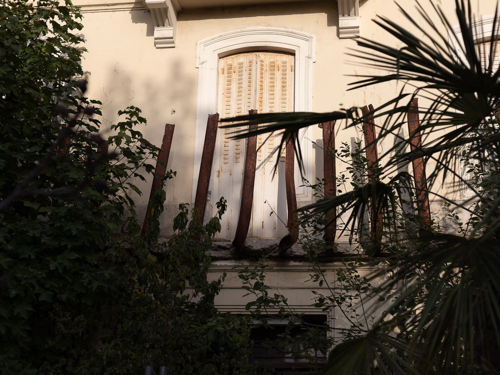 Bâtiment abandonné aux poutres du balcon repliés, entouré de végétation luxuriante