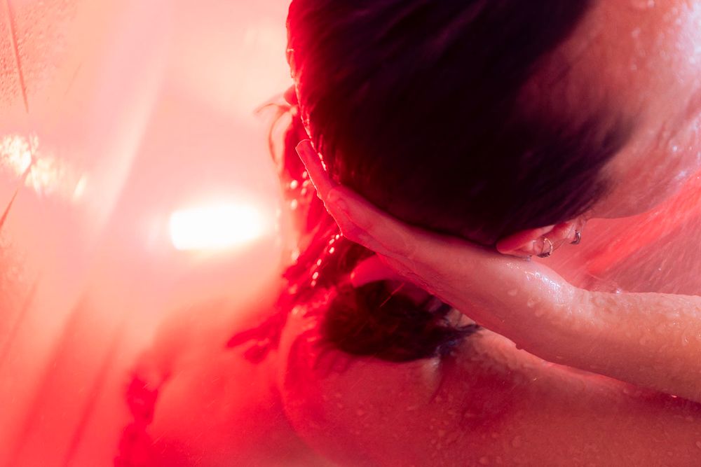 Détails de corps féminin sous la douche, dans une lumière rouge
