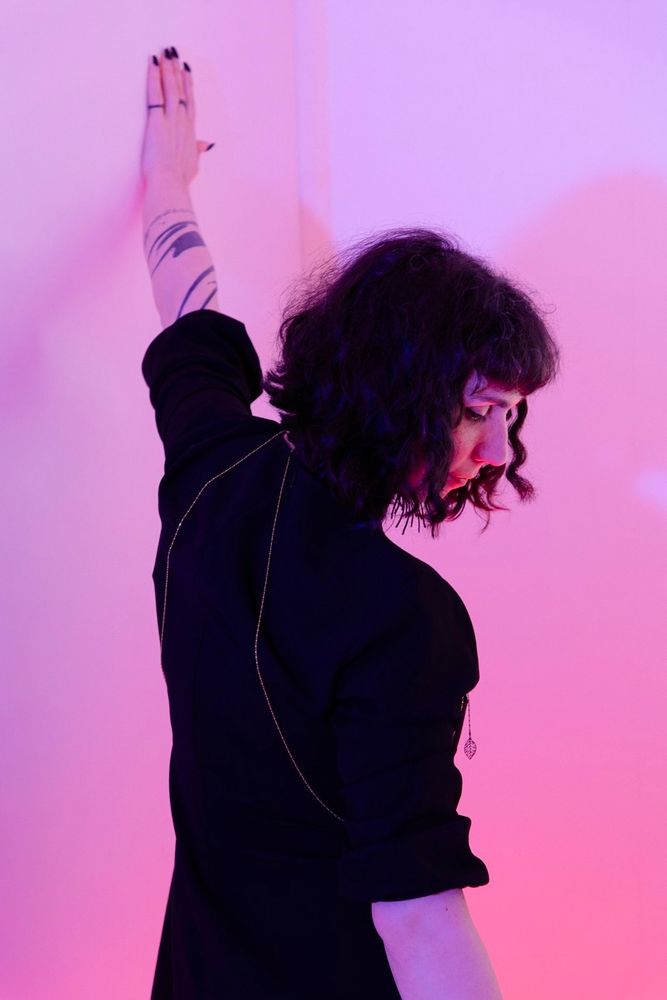 Portrait de dos dans une lumière douce aux tonalités roses / violettes.
