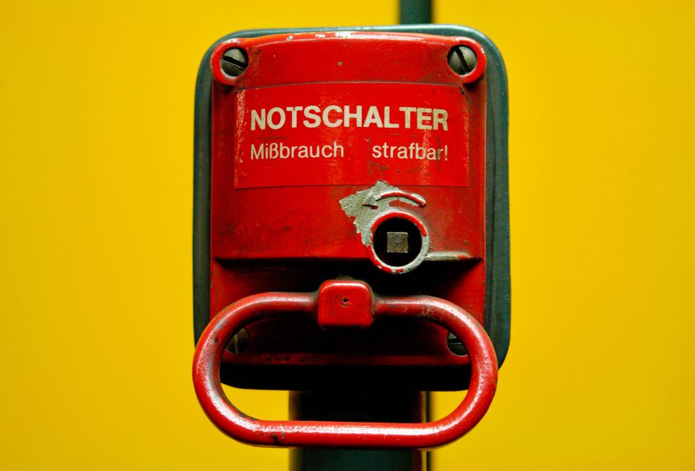 Notbremse mit der Aufschrift Notschalter in Rot an gelber Wand.