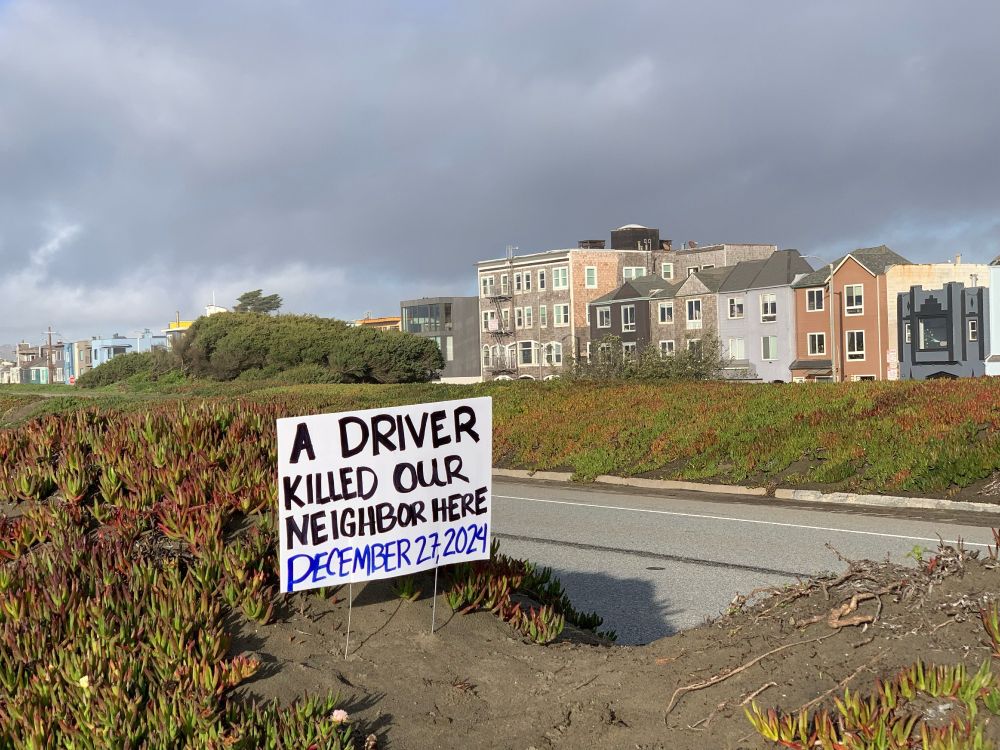 A driver killed our neighbor here December 27, 2024. Handwritten sign in median of highway.