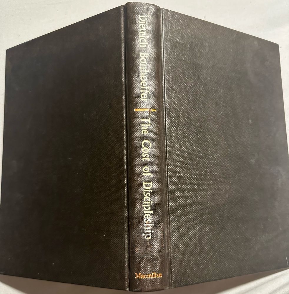 A hardcover copy of “The Cost of Discipleship” by Dietrich Bonhoeffer, lying open and face down.