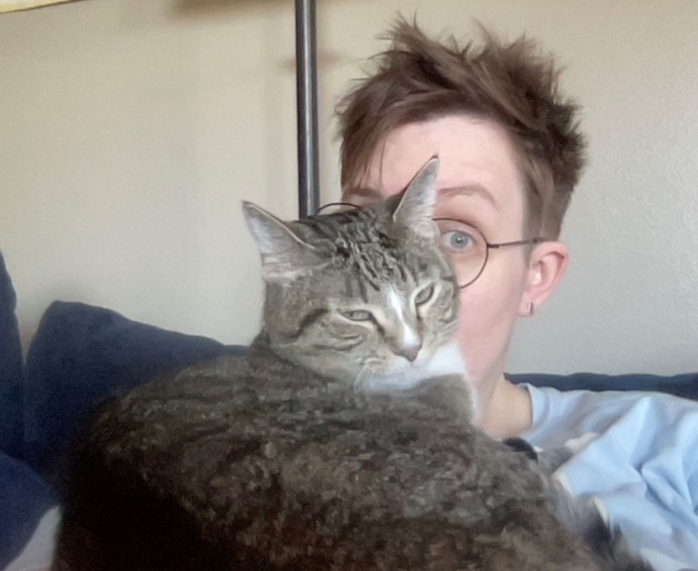 Gorgeous striped tabby sits on top of Allison, blocking her mouth and nose, in a snuggle-smother attempt