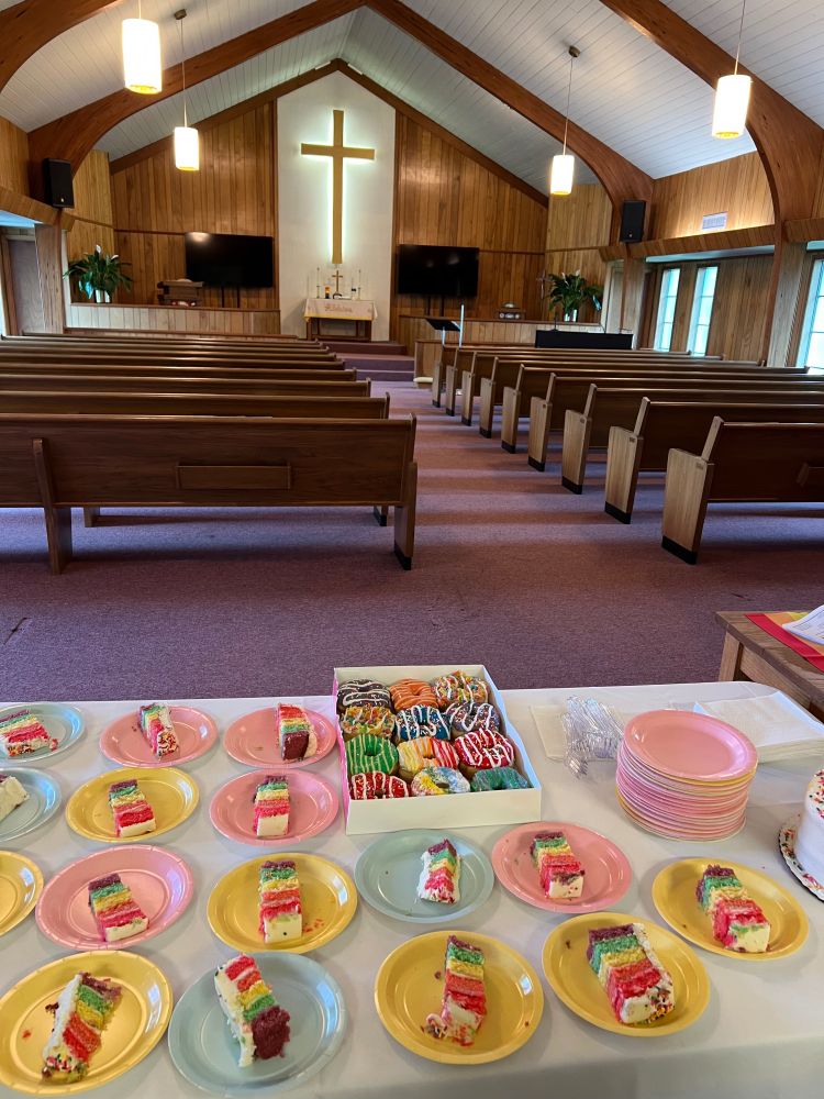 A table laid with rainbow cake and pride donuts set up in a church sanctuary in Mississippi.