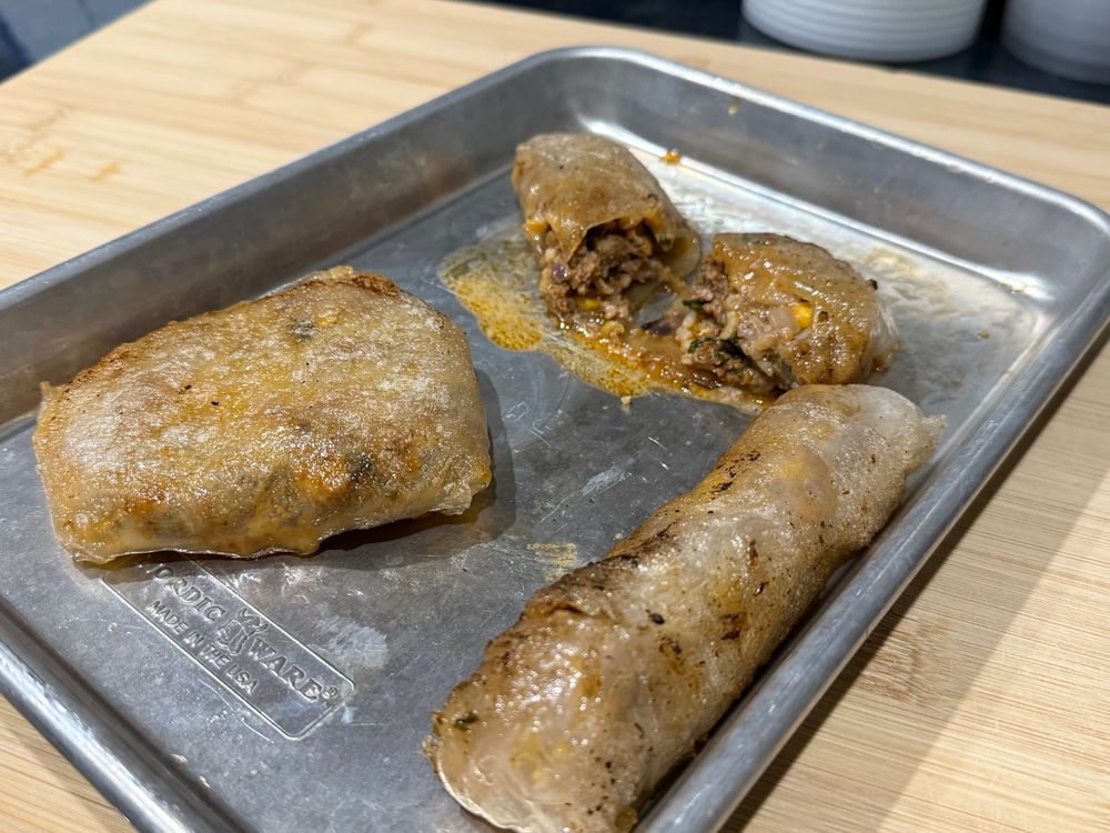 Crispy spring rolls and a patty on a small cookie sheet 