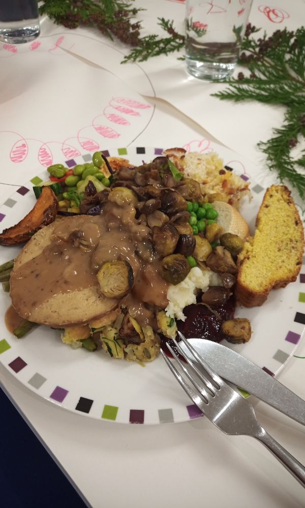 A large plate piled with an enormous quantity and variety of thanksgiving foods. Visible items include (tofu) turkey and gravy, sprouts and chestnuts, roast squash, edamame and cucumber salad, macaroni cheese, mashed potato, peas, cranberry sauce, green bean casserole, cornbread, regular bread, bread stuffing. Not pictured, the dessert selection which included multiple types of pumpkin, apple and pecan pies, sticky ginger cake, cream and ice cream.