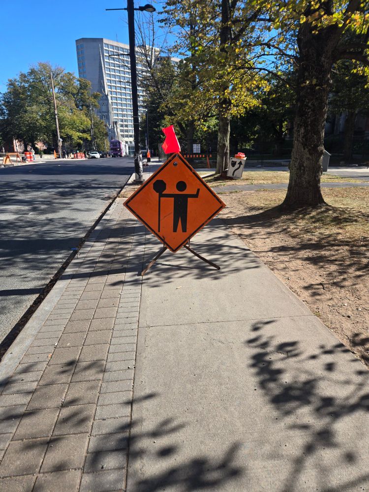 Construction sign almost entirely blocking an open sidewalk.
