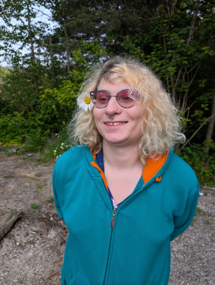 us in our blue and orange ripzone skater hoodie smiling at the camera with our glasses transitioned to pink with a flower we believe a daisy in our floof 
