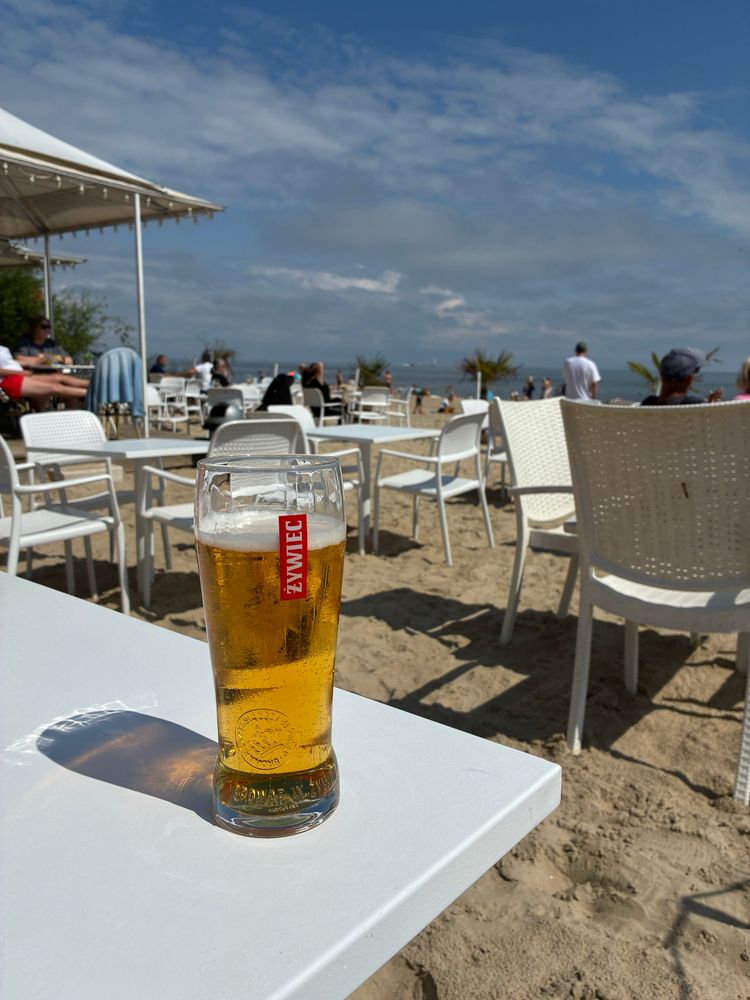 View from a bar at the beach with a freshly drawn beer on the table. 