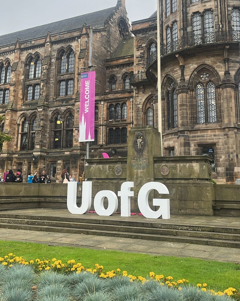 A photo of the front of the main UofG campus building with UofG in big white letters sitting on the steps as a welcome to guests