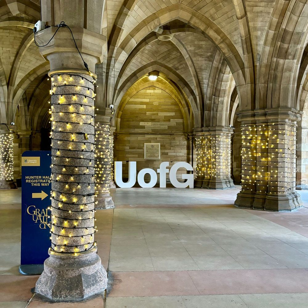 White letters spelling UofG in the Cloisters which are wrapped in festive lights during graduation
