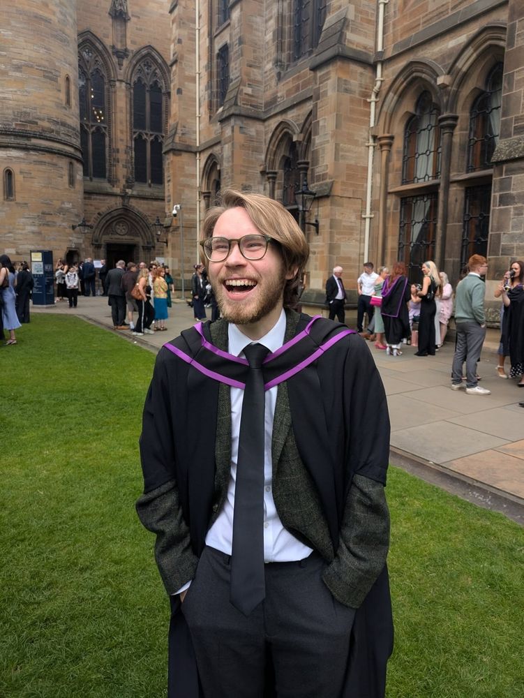A laughing graduate standing in the quads.