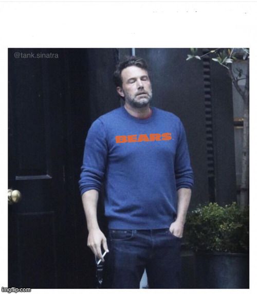 Ben Affleck smoking outside a black door, with his eyes closed and face forlorn like he's just tired of shit. On his blue sweatshirt is badly-photoshopped Chicago Bears wordmark.