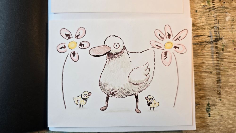 A goose platypus with two chick's in between two huge flowers.