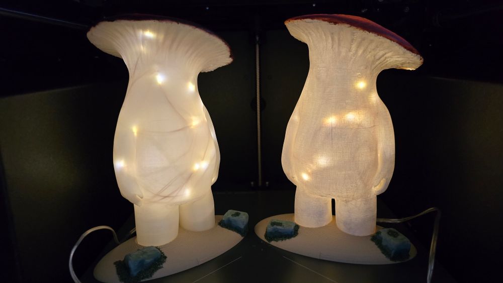 Two mushroom people from Dark Souls on a base with mossy stones slightly glowing.